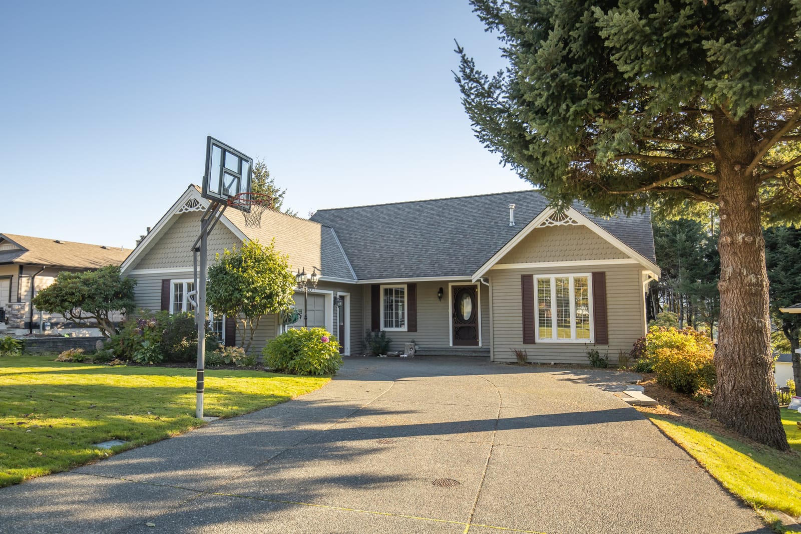Modest home with concrete driveway and basketball hoop
